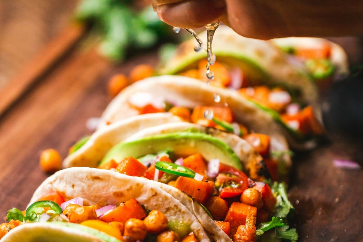 Warm corn tortillas topped with crispy shredded pork carnitas, diced white onions, cilantro, and fresh lime wedges
