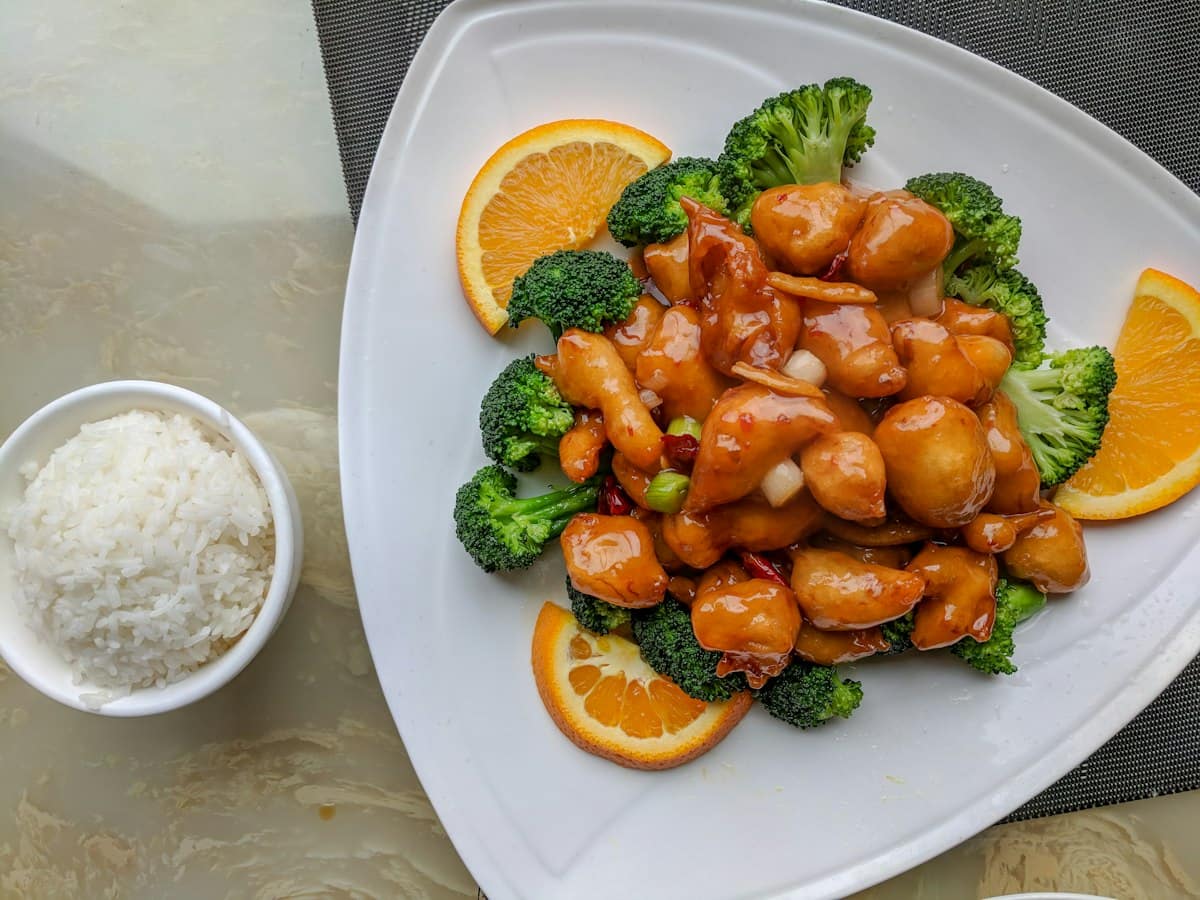 Sizzling wok of authentic Sichuan Kung Pao Chicken (Gong Bao Ji Ding) showing tender diced chicken, toasted peanuts, whole dried red chilies, and scallions in glossy vinegar sauce