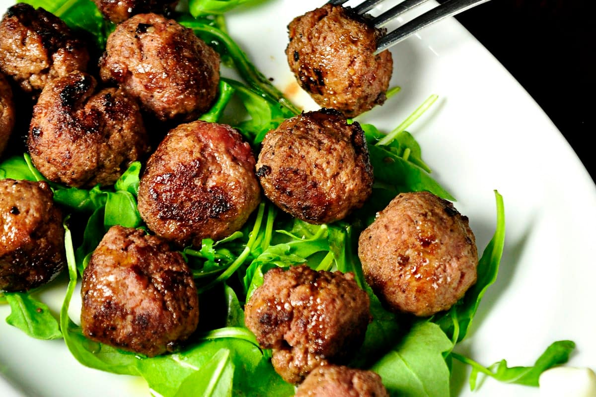 Golden browned Swedish meatballs smothered in velvety spiced cream gravy served in a skillet with creamy mashed potatoes and lingonberry jam