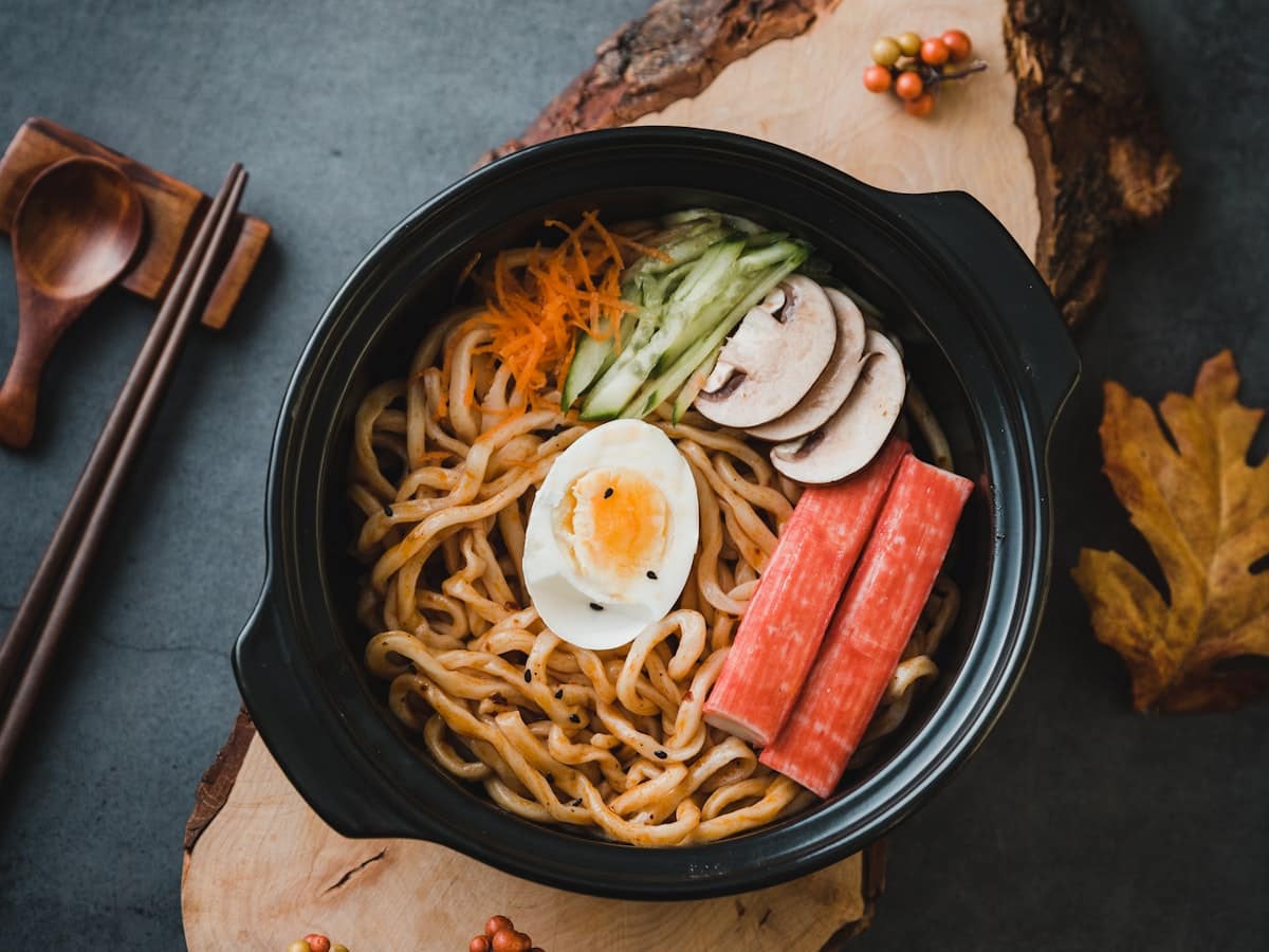 Thick bouncy udon noodles tossed in sizzling spicy chili garlic scallion oil with jammy soft boiled egg and fresh vegetable garnishes