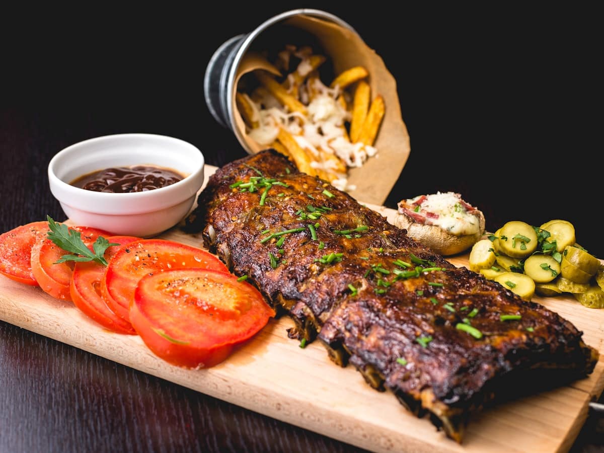 Sizzling pan-seared Turkish spiced lamb kofte skewers with charred edges, served with fresh herbs, lemon wedges, and creamy garlic tahini yogurt sauce