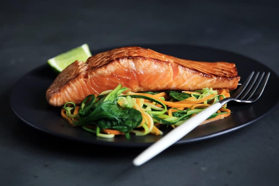 Pan-seared crispy skin salmon fillet in a glossy lemon caper butter pan sauce with fresh herbs and lemon slices