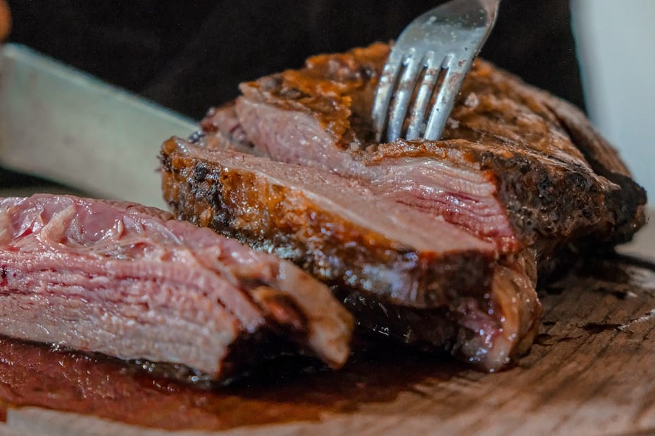 Juicy medium rare pan seared ribeye steak carved into thick tender slices showing golden brown caramelized crust on a rustic cutting board