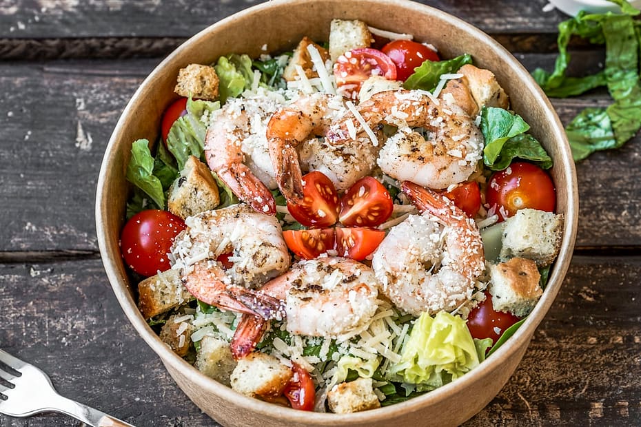 Plump golden brown pan seared jumbo shrimp tossed in garlic butter with freshly grated Parmesan cheese, herbs, and lemon in a wooden bowl
