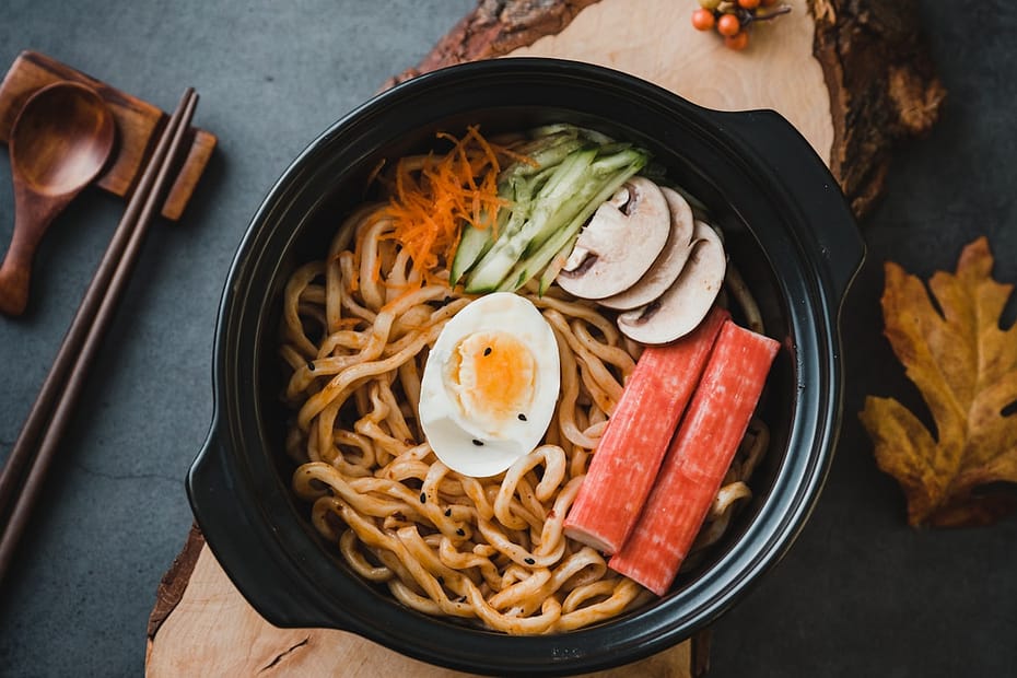 Thick bouncy udon noodles tossed in sizzling spicy chili garlic scallion oil with jammy soft boiled egg and fresh vegetable garnishes