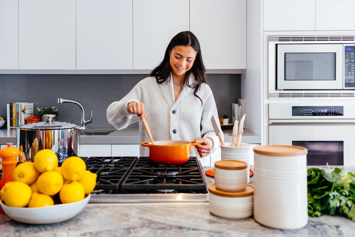 A wooden spoon resting across the rim of a boiling saucepan on a stovetop